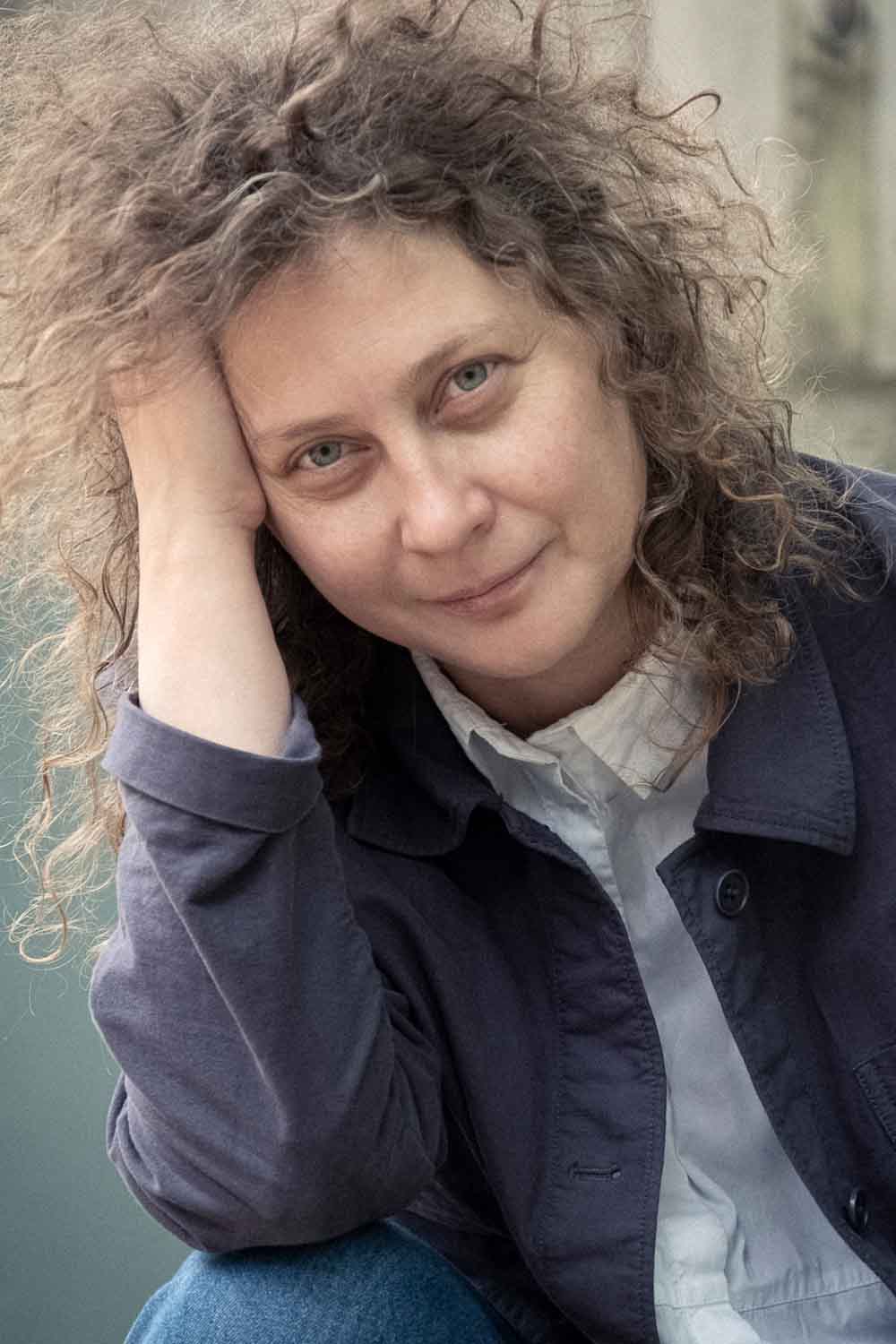 Zielinski.Photography - Images of artworks and culture - Berlin A woman with curly hair posing against a wall in an artistic photograph.