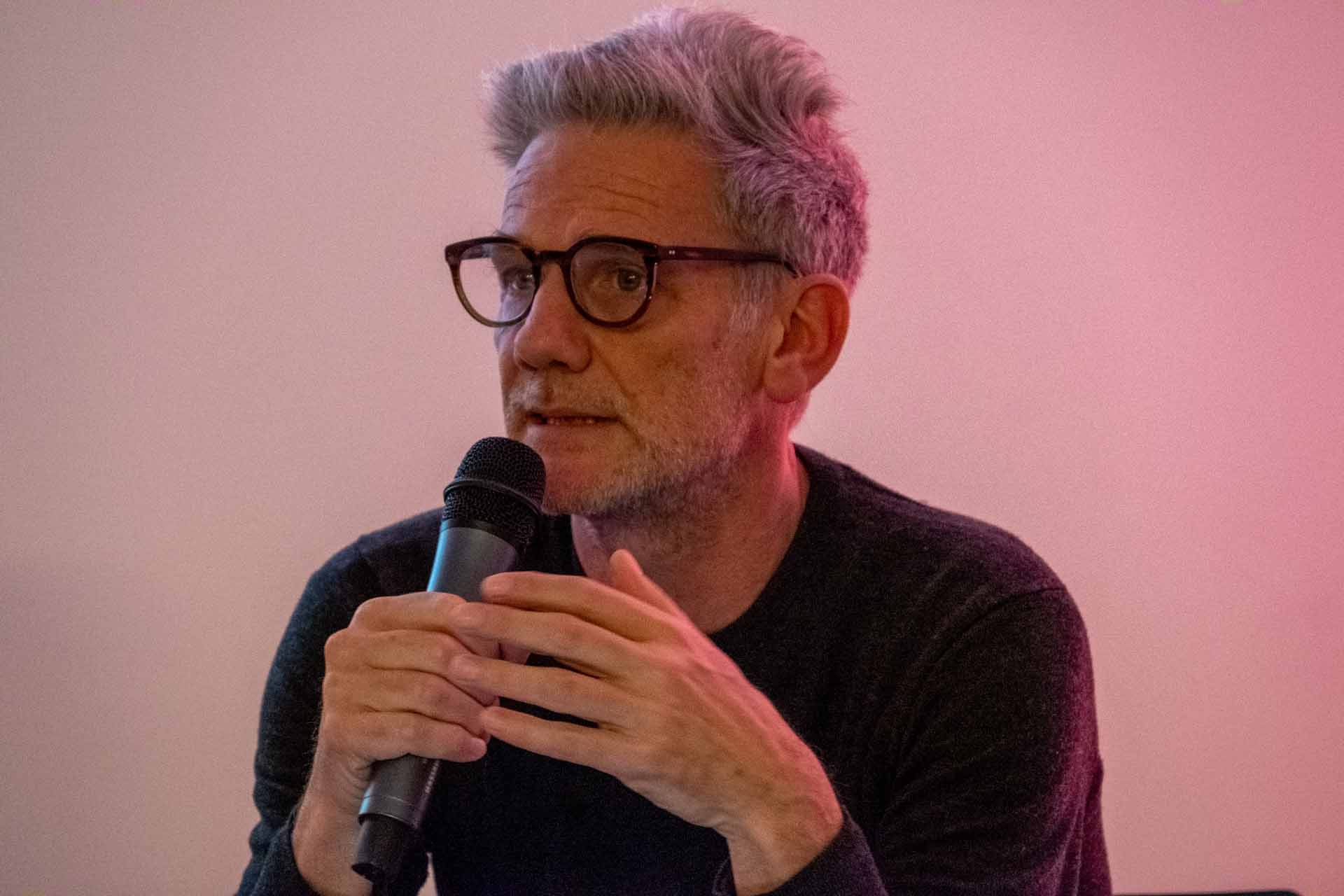 Zielinski.Photography - Images of artworks and culture - Berlin A man, wearing glasses, is giving a performance while speaking into a microphone.