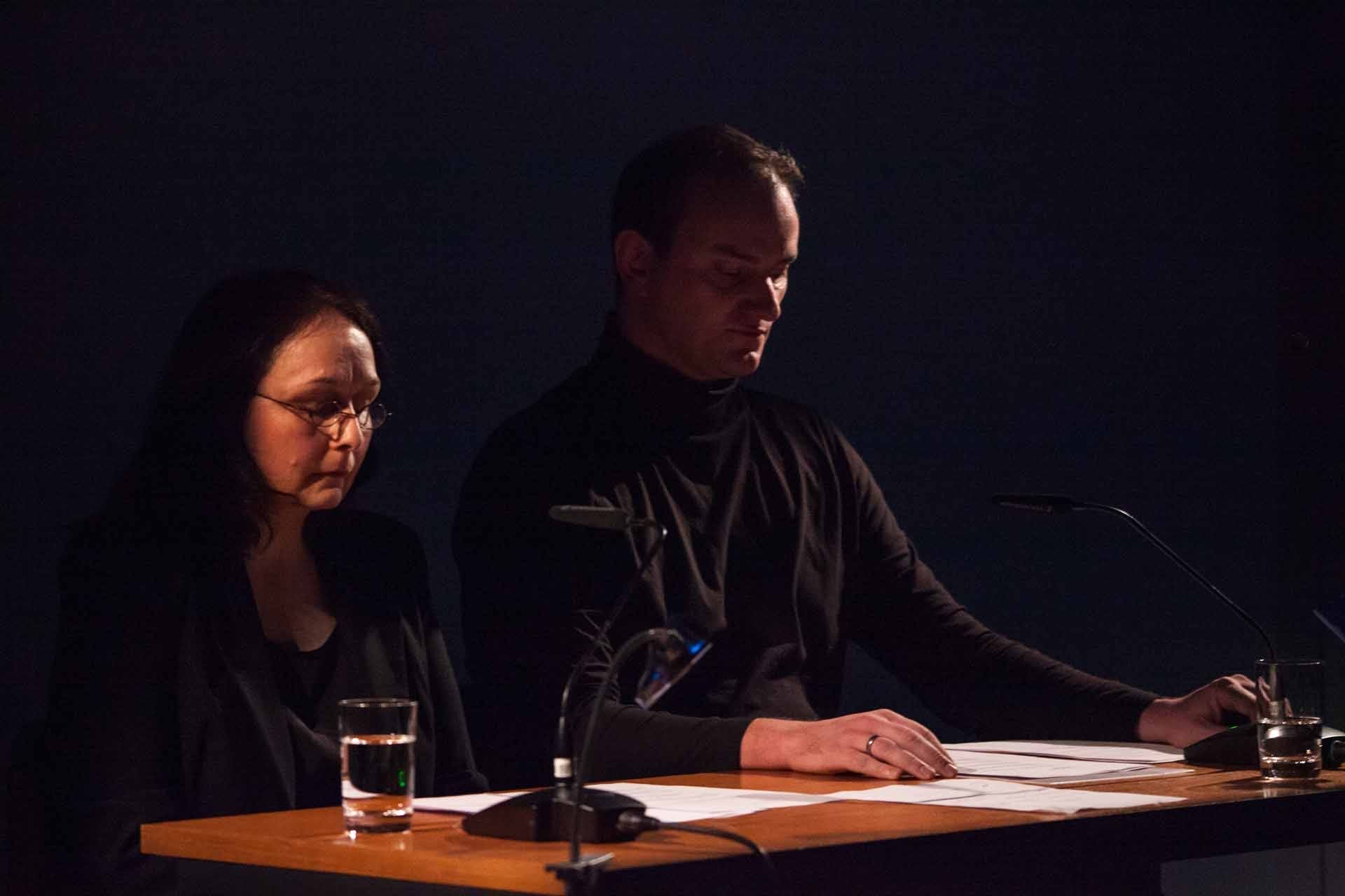 Zielinski.Photography - Images of artworks and culture - Berlin A man and a woman sitting at a table in a dark room, surrounded by artworks.