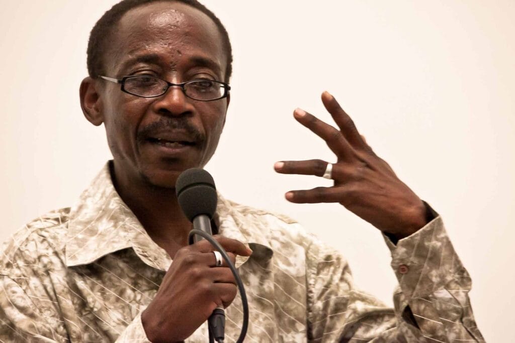 Zielinski.Photography - Images of artworks and culture - Berlin A man in a camouflage shirt is performing, speaking into a microphone while showcasing his artistic talents.