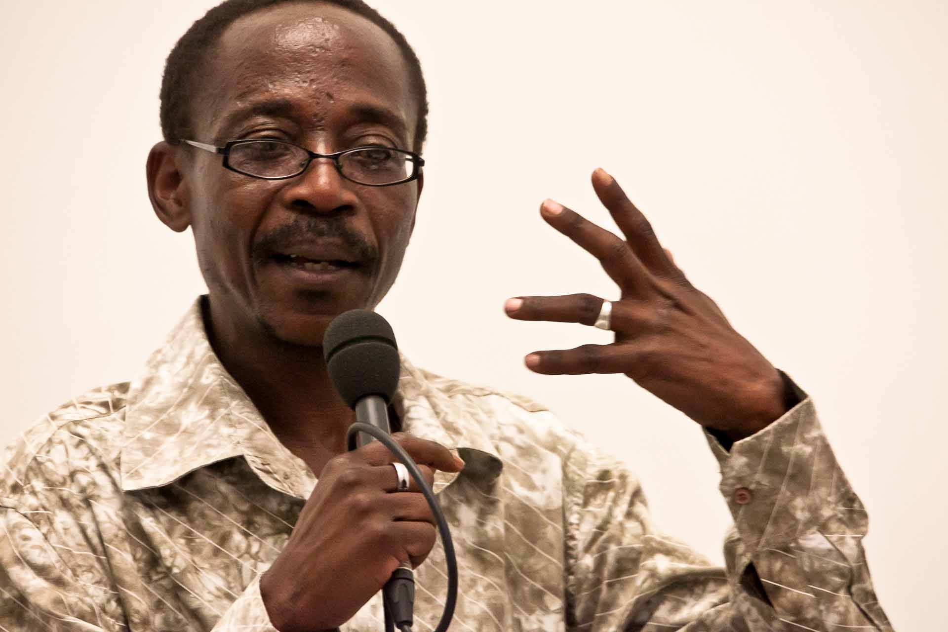 Zielinski.Photography - Images of artworks and culture - Berlin A man in a camouflage shirt is performing, speaking into a microphone while showcasing his artistic talents.