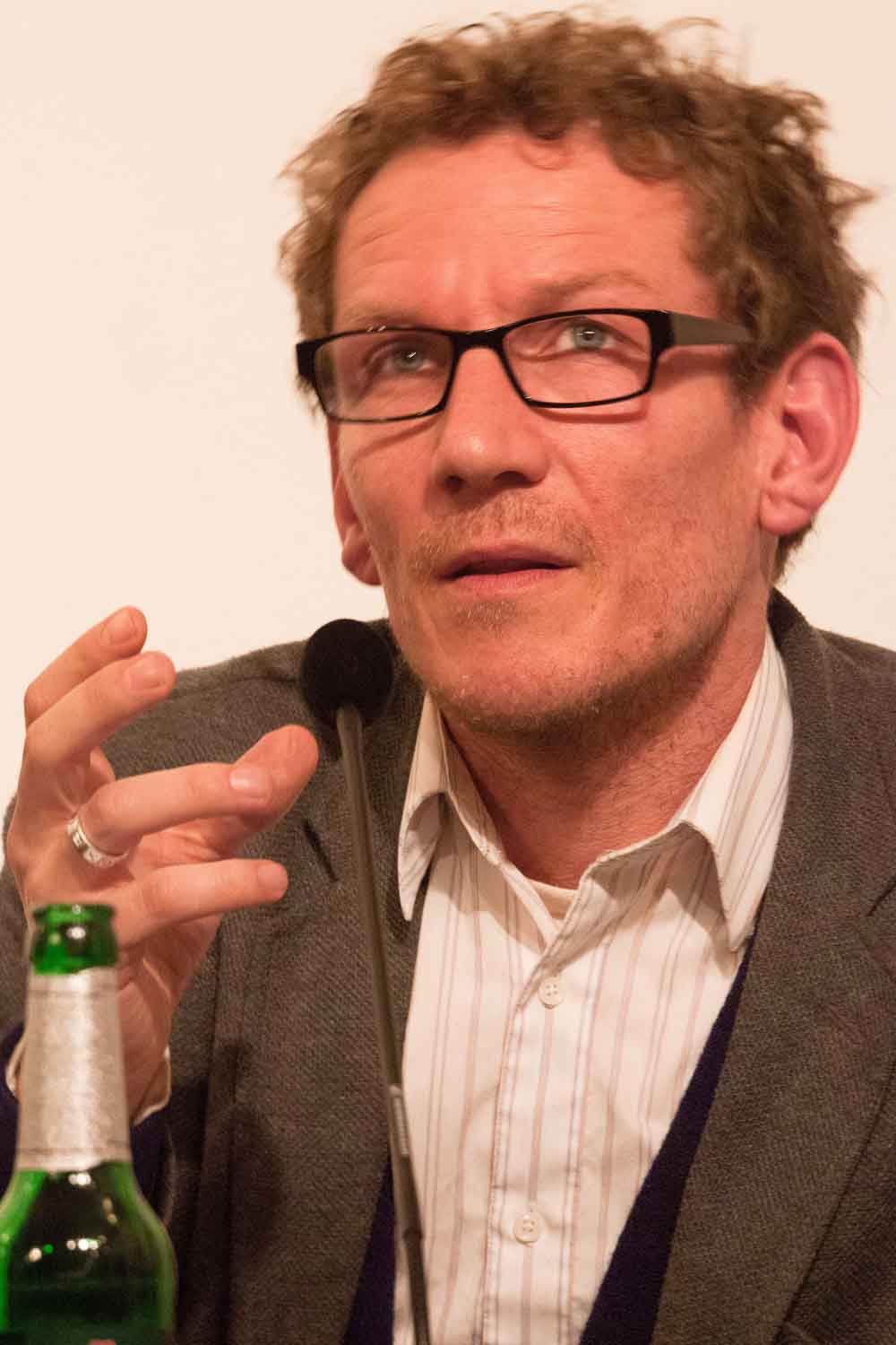 Zielinski.Photography - Images of artworks and culture - Berlin A man in glasses is holding a bottle of beer at an art exhibition.