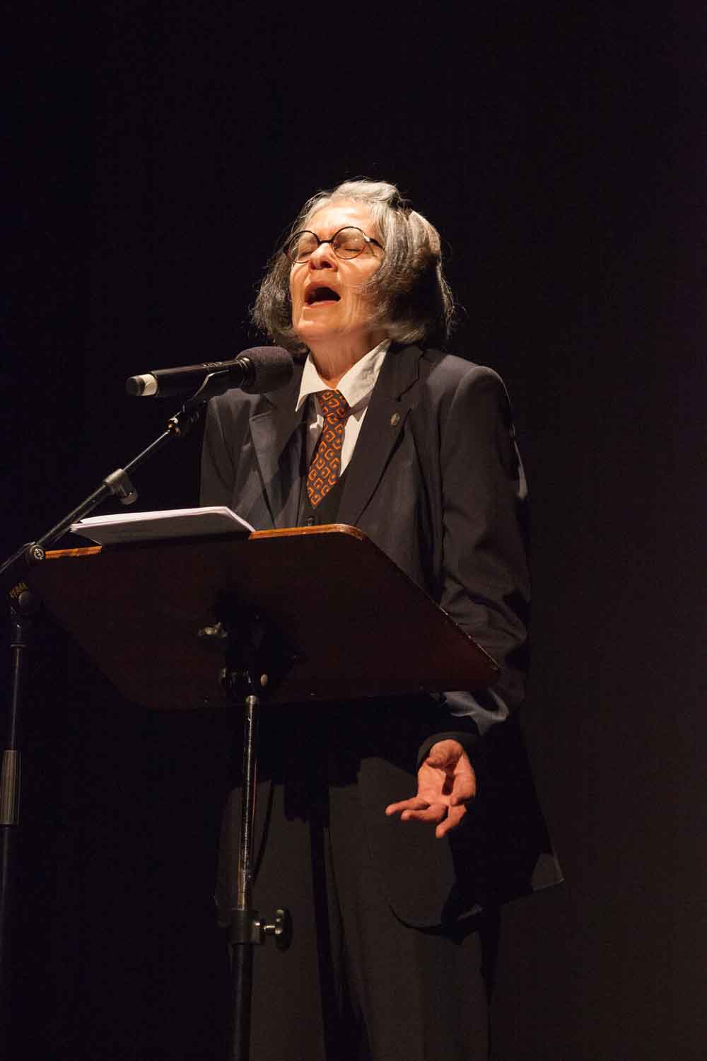Zielinski.Photography - Images of artworks and culture - Berlin A woman in a suit speaking into a microphone at an exhibition showcasing Zielinski's artworks.
