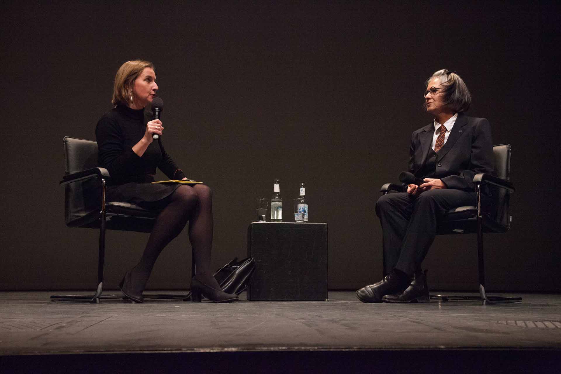 Zielinski.Photography - Images of artworks and culture - Berlin Two women sitting on stage engaging in a conversation during an artistic event.