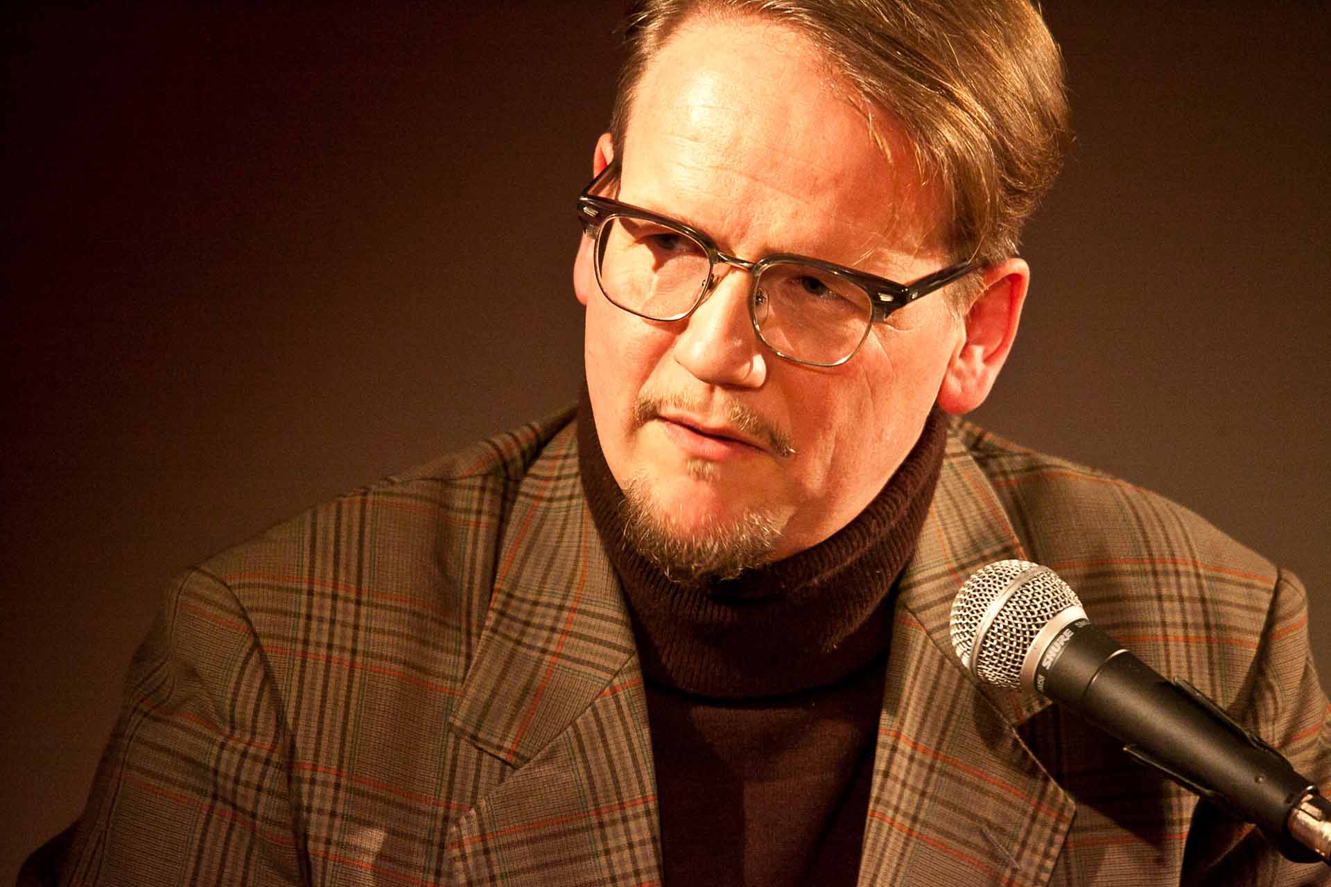 Zielinski.Photography - Images of artworks and culture - Berlin A man in glasses is speaking into a microphone, capturing the moment with photography.