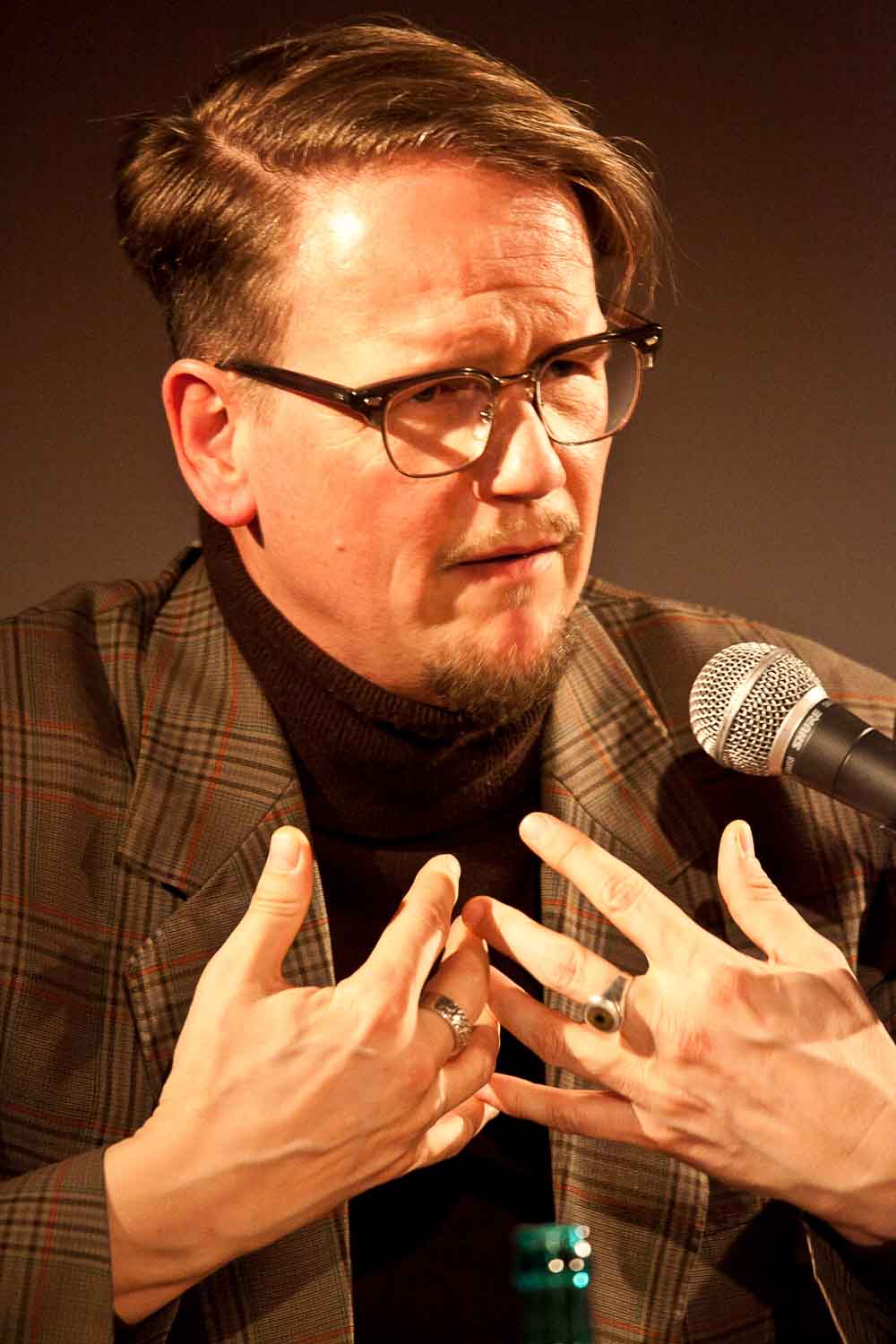 Zielinski.Photography - Images of artworks and culture - Berlin A man in glasses is delivering a captivating performance into a microphone at an exhibition.