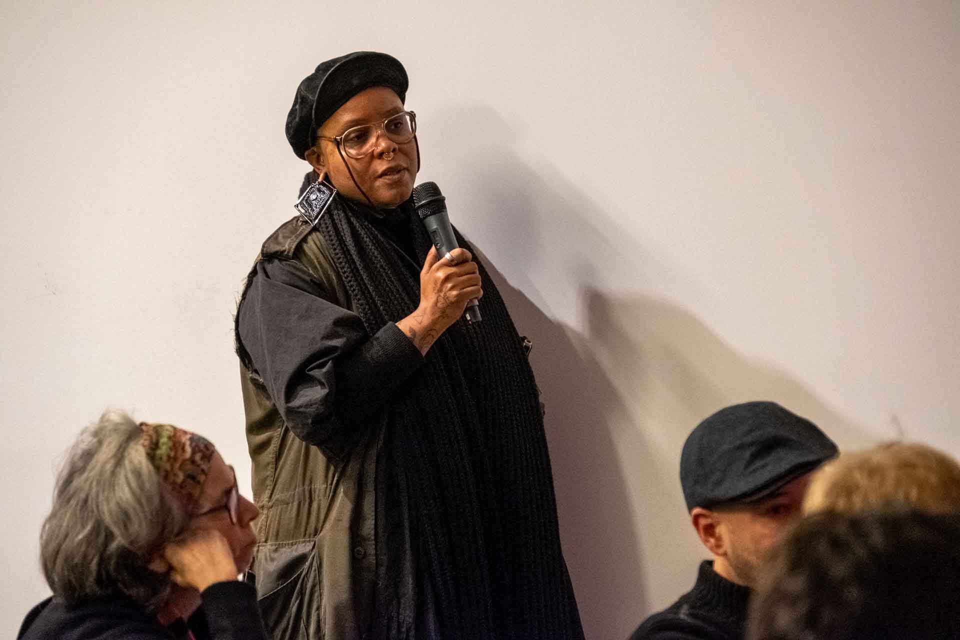 Zielinski.Photography - Images of artworks and culture - Berlin Zielinski, a woman, speaking into a microphone in front of a group of people about literature and music.