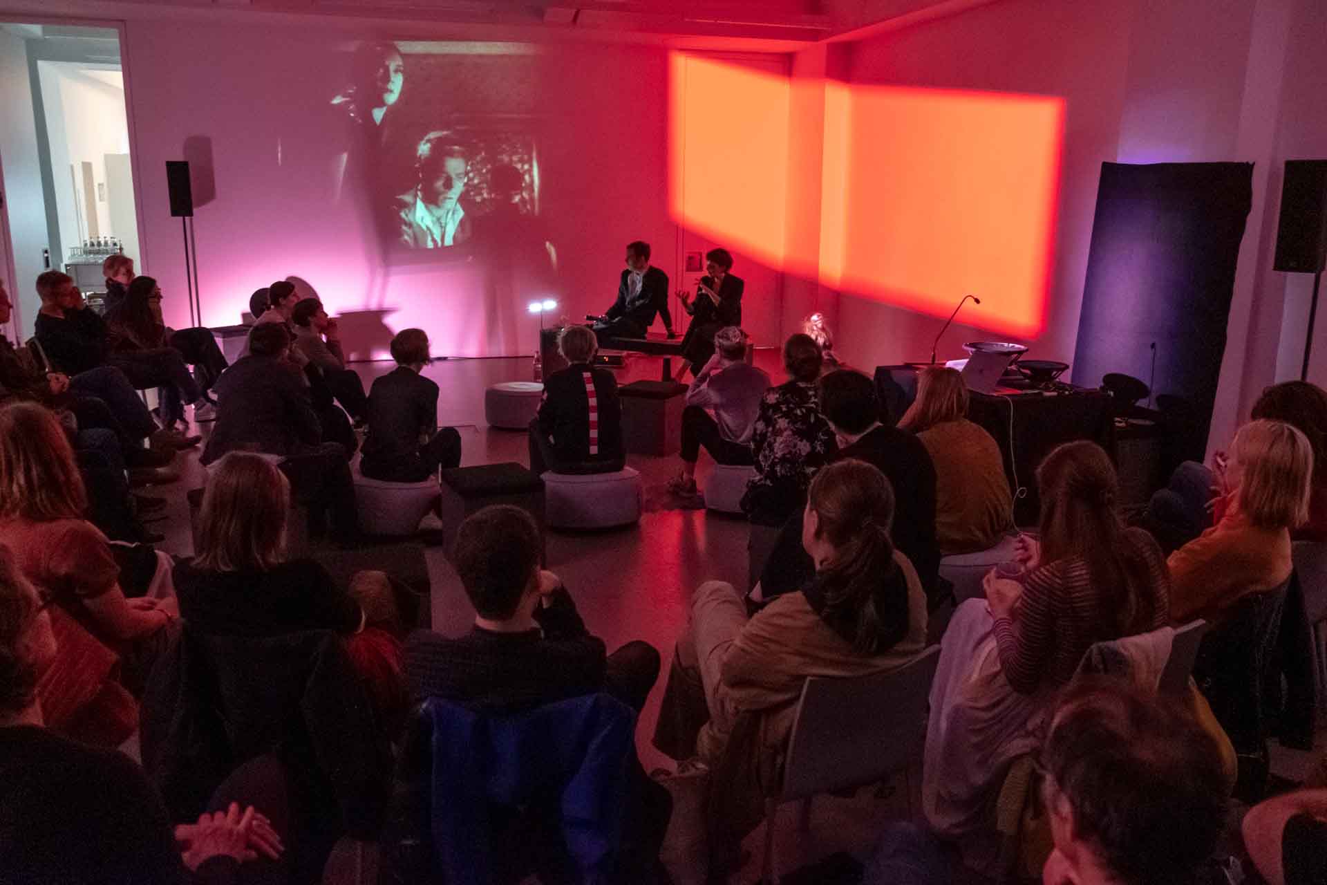 Zielinski.Photography - Images of artworks and culture - Berlin Zielinski and a group of people sitting in a room watching a photography projection performance.