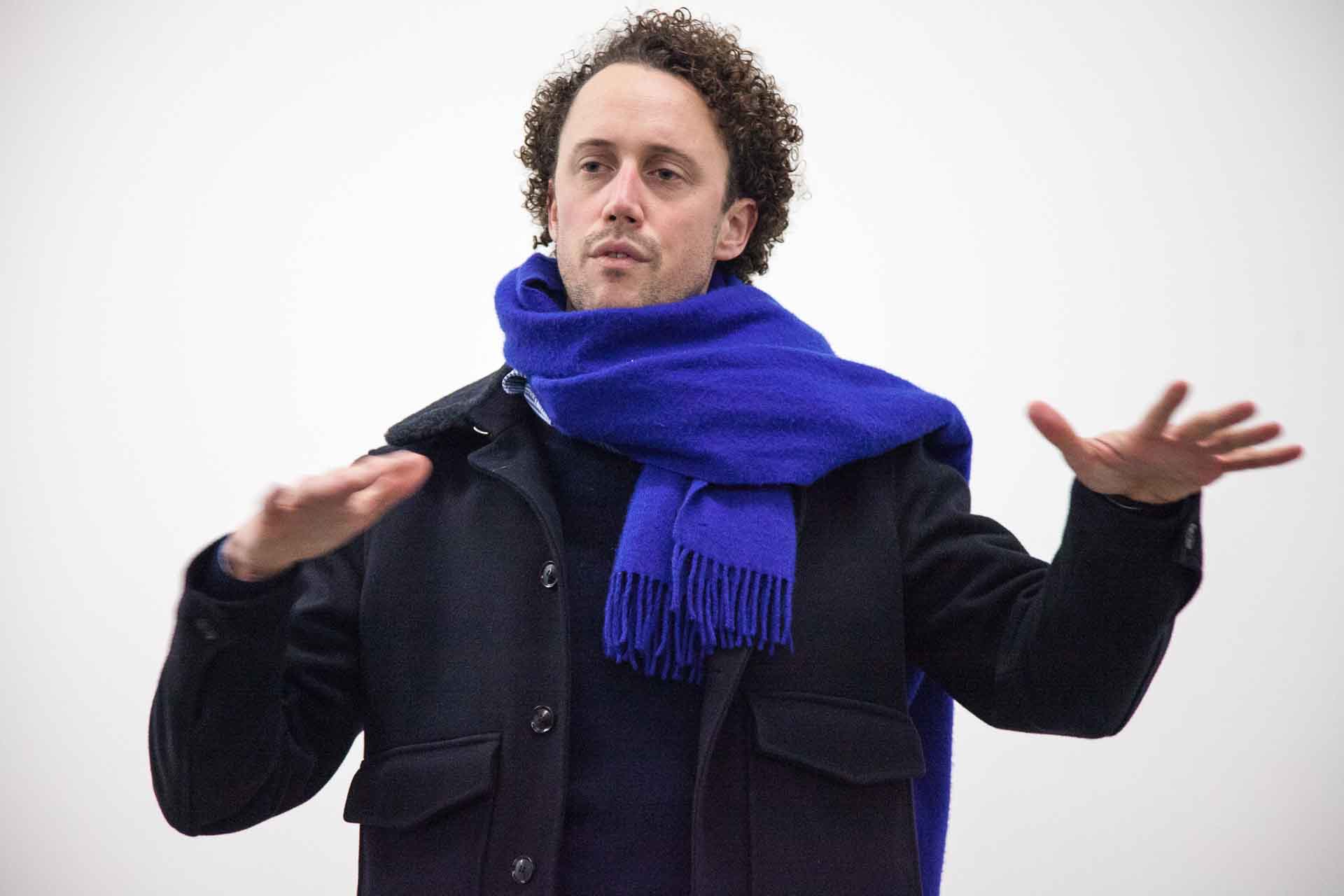 Zielinski.Photography - Images of artworks and culture - Berlin Zielinski, a man in a blue scarf, mesmerizes the audience with his exceptional performance during an exhibition as he gracefully extends his hands outstretched.