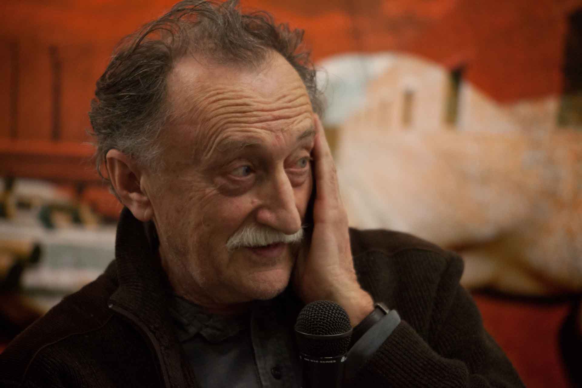 Zielinski.Photography - Images of artworks and culture - Berlin A man with a moustache is holding a microphone, capturing the artworks in an exhibition for documentation purposes.