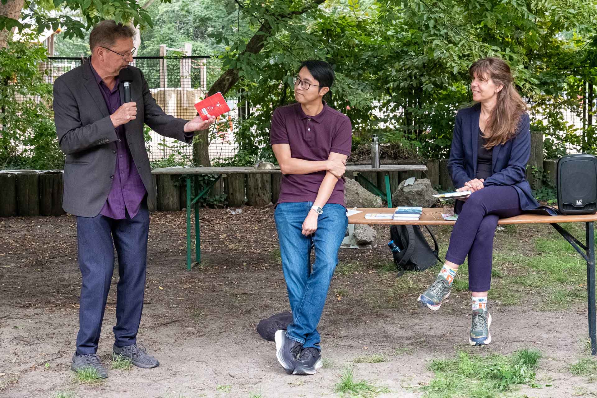 Zielinski.Photography - Images of artworks and culture - Berlin A group of people engaging in a creative photography exhibition at a table in a park.