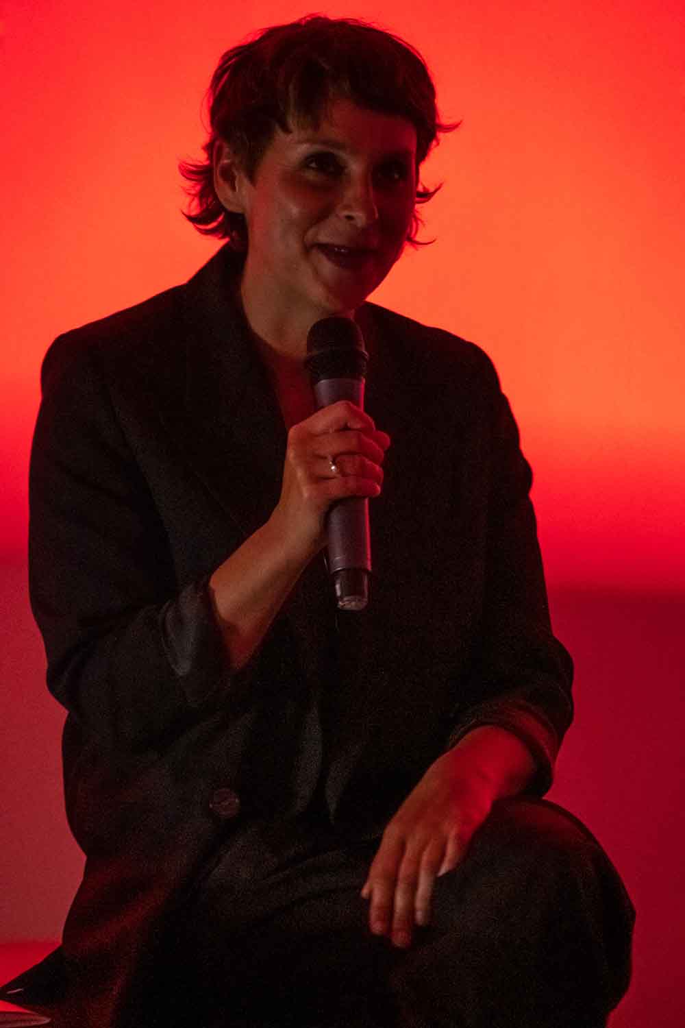 Zielinski.Photography - Images of artworks and culture - Berlin A woman giving a performance with a microphone in front of a red light.