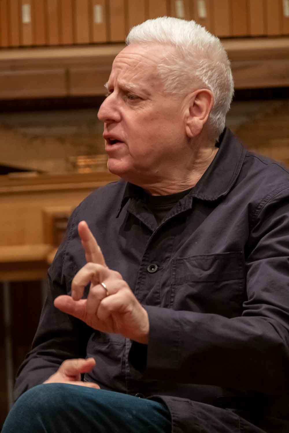 Zielinski.Photography - Images of artworks and culture - Berlin Zielinski, wearing a black jacket, is captured in a photography documentation while sitting in front of a piano.