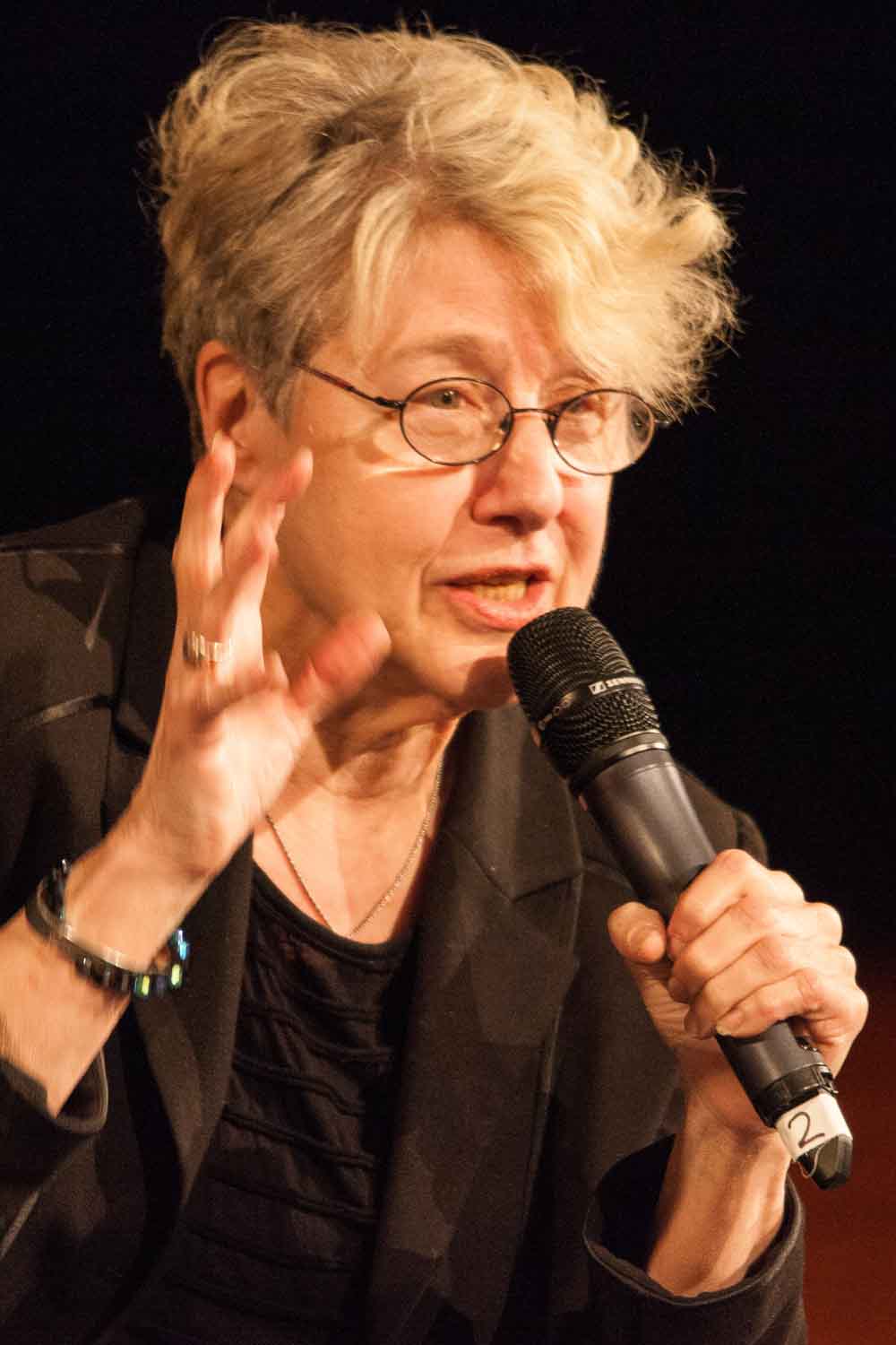 Zielinski.Photography - Images of artworks and culture - Berlin A woman with glasses speaking into a microphone, discussing literature.