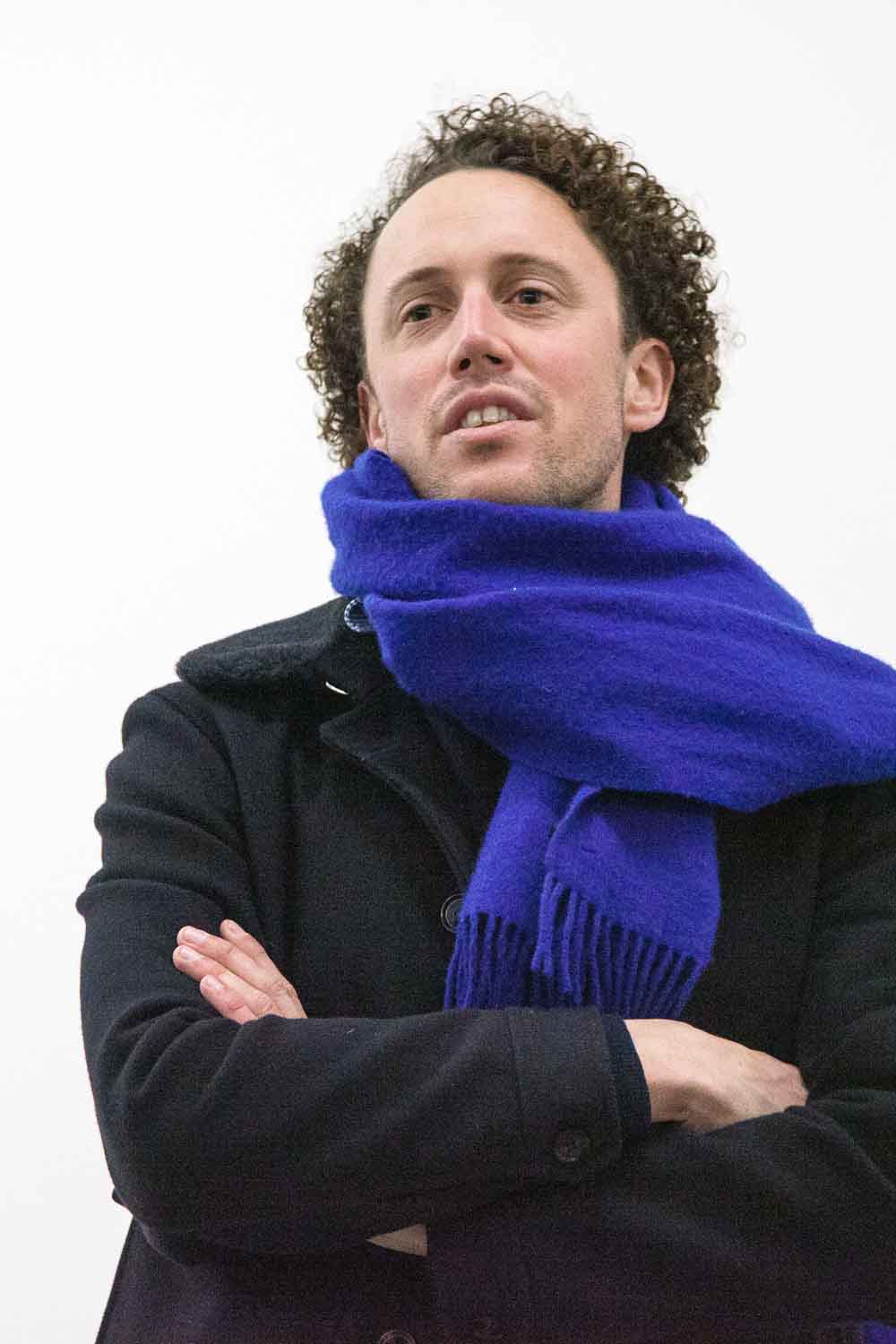 Zielinski.Photography - Images of artworks and culture - Berlin A man with curly hair captured in a photography exhibition wearing a blue scarf.