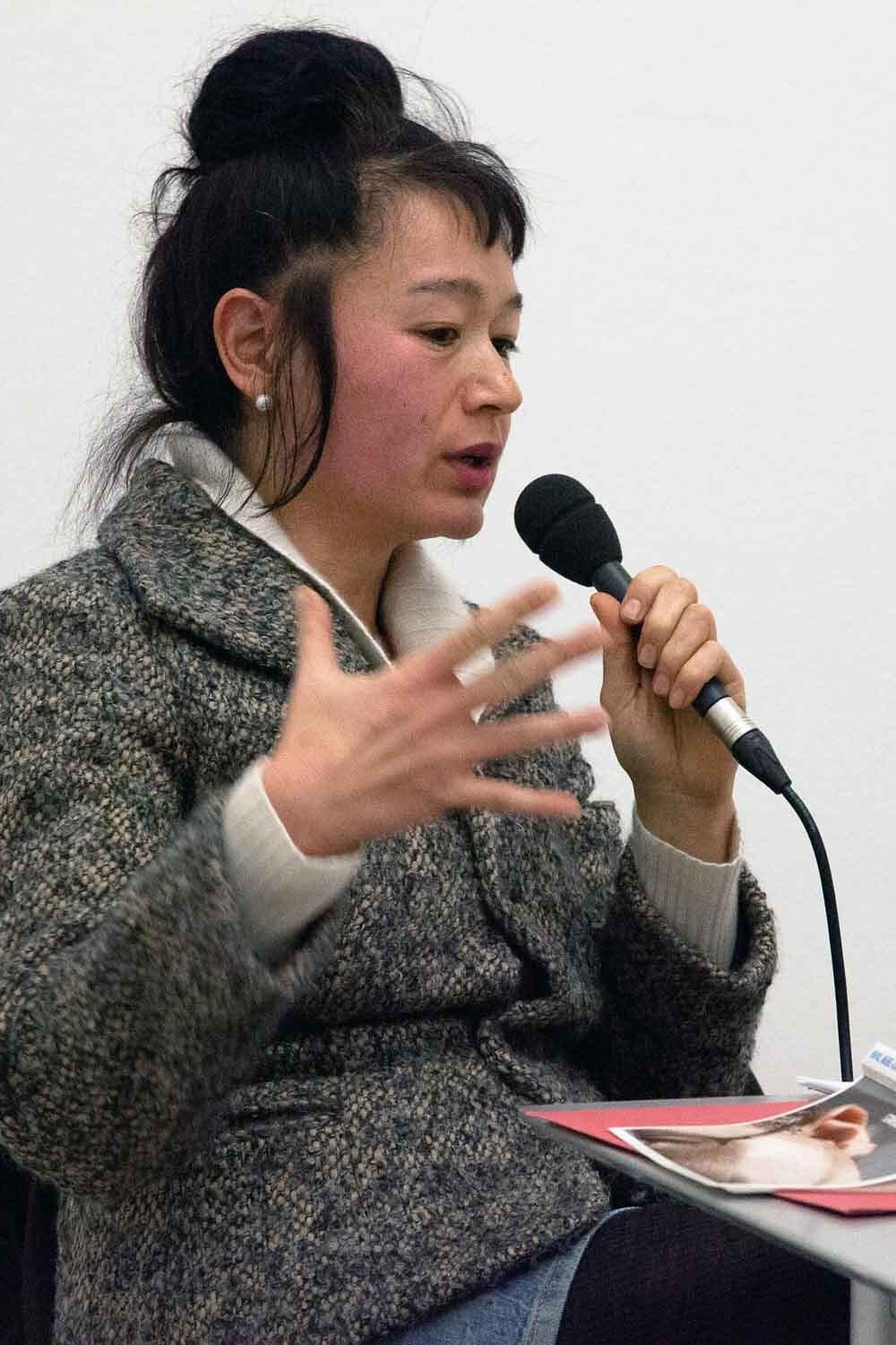 Zielinski.Photography - Images of artworks and culture - Berlin A woman giving a performance while speaking into a microphone at an exhibition.