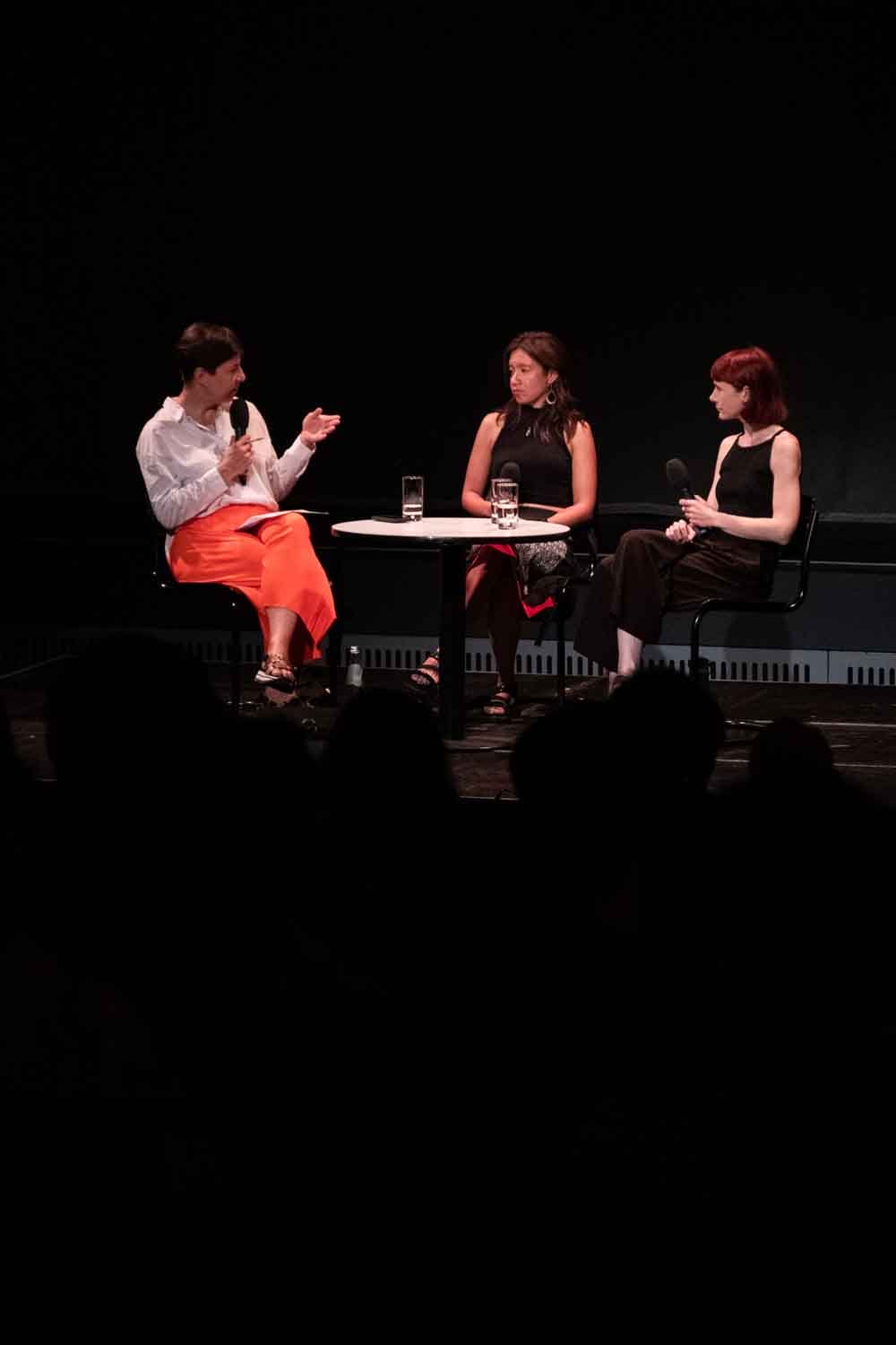 Zielinski.Photography - Images of artworks and culture - Berlin Three women sitting on stage in front of a dark room.