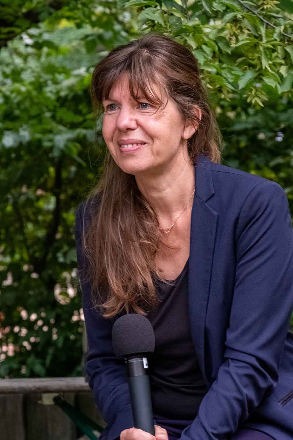 Zielinski.Photography - Images of artworks and culture - Berlin Michaela Vieser sitting on a bench with a microphone.